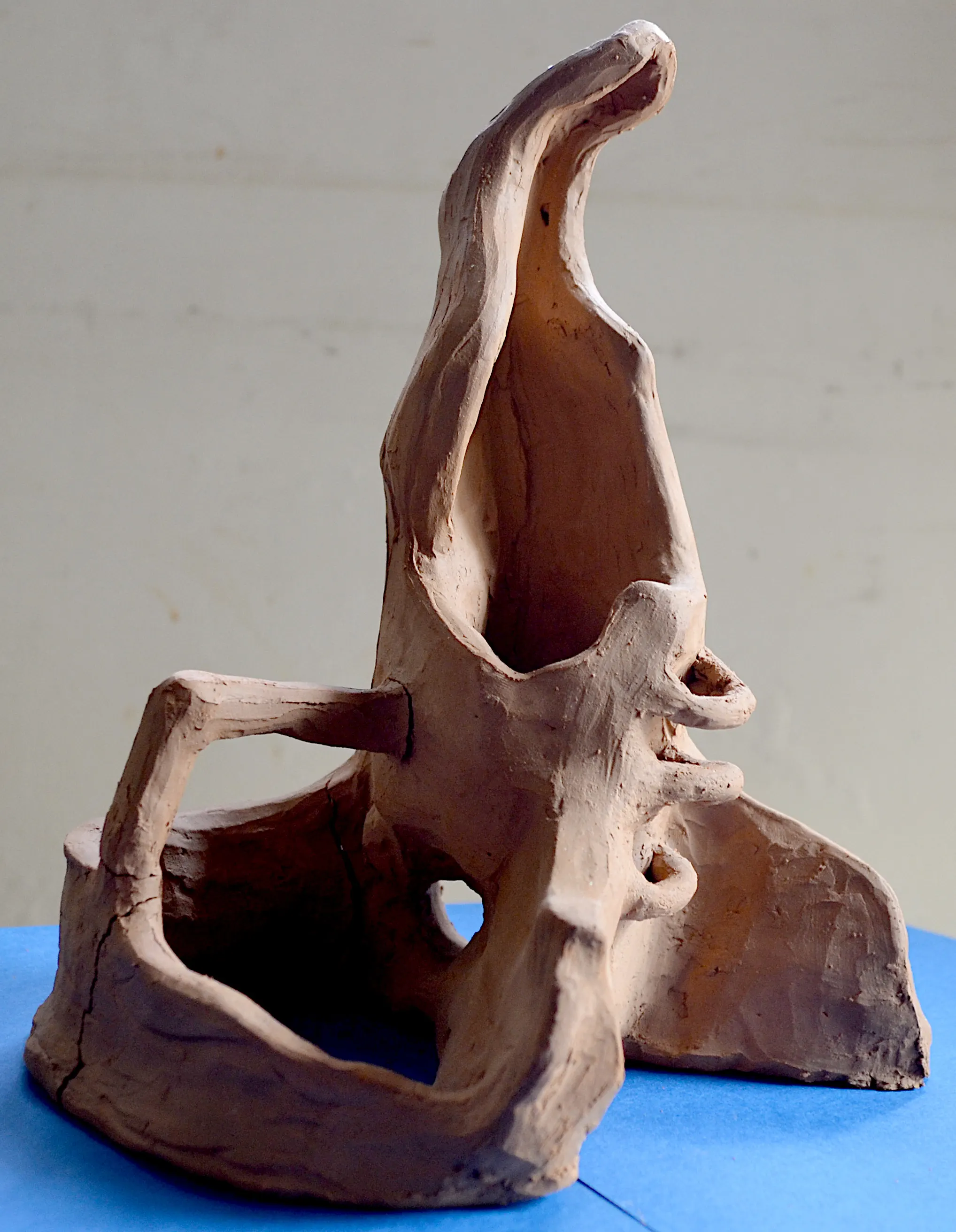 Open abstract terracotta sculpture with a rising curved form and intersecting chambers